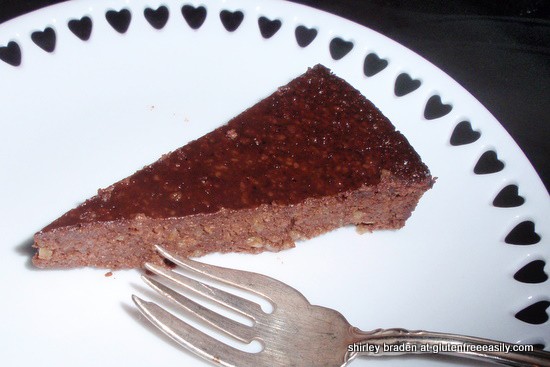 Slice of Flourless Chocolate Banana Honey Walnut Cake on white plate with cut-out hearts. One of 25 gluten-free chocolate cakes on glutenfreeeasily.com.