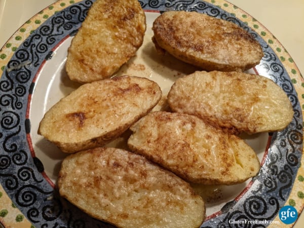 Gluten-Free Pan-Baked Potatoes Cooked in the Microwave. Six halves on a decorative plate.