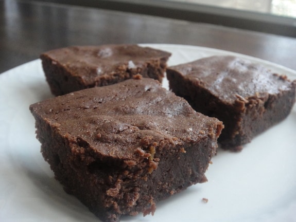 Three Big and Rich Gluten-Free Brownies on a white plate on sideboard by window.