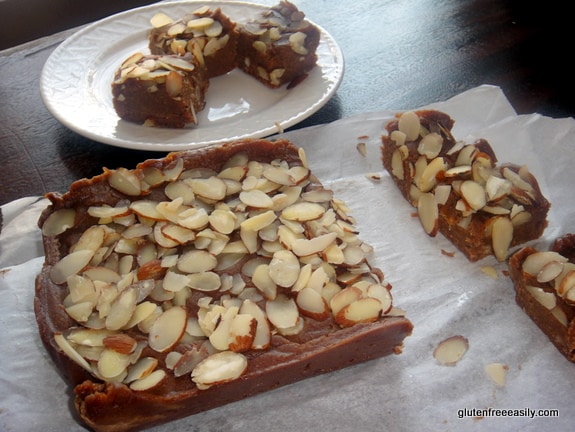 Cinnamon Almond Fudge from Desserts Without Compromise. Slab of cinnamon fudge topped with sliced almonds. Piece of fudge on a separate plate.