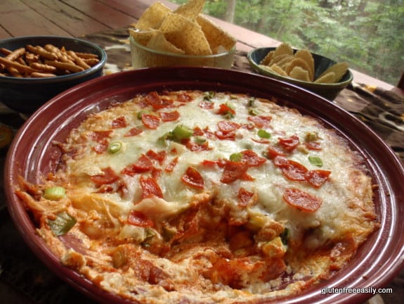 Pizza Dip in pie plate with bowls of ingredients for dipping--gf pretzels, tortilla chips, and potato chips. Naturally Gluten-Free Pizza Dip at Gluten Free Easily. I bet you can think of a ton of ways to serve this!