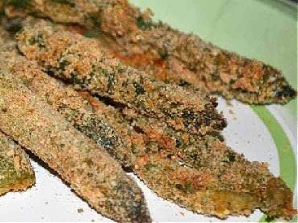 Gluten-Free Asparagus Fries. Asparagus spears coated in egg and bread crumbs on a white plate banded with green.