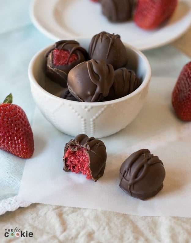 Stawberry-Filled Chocolate Truffles on parchment paper and in a bowl.