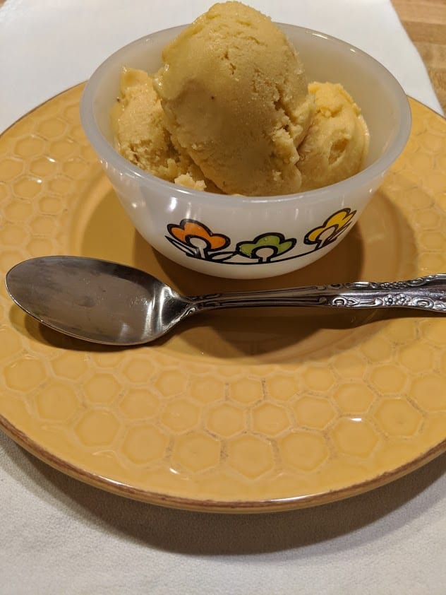 More than a scoop of homemade dairy-free mango ice cream in bowl.