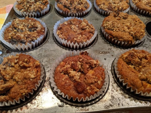 Gluten-free and paleo Apple Crumb Muffins in old Ecco muffin tin cooling on plaid cotton dish towel.