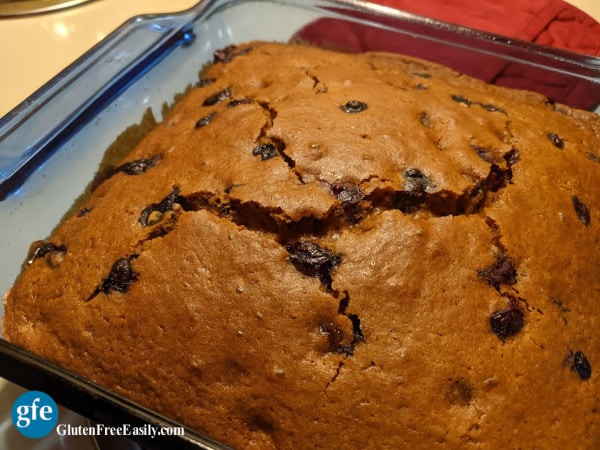 Gluten-Free Blueberry Gingerbread Recipe with cracked top in blue square baking dish. On Gluten Free Easily.