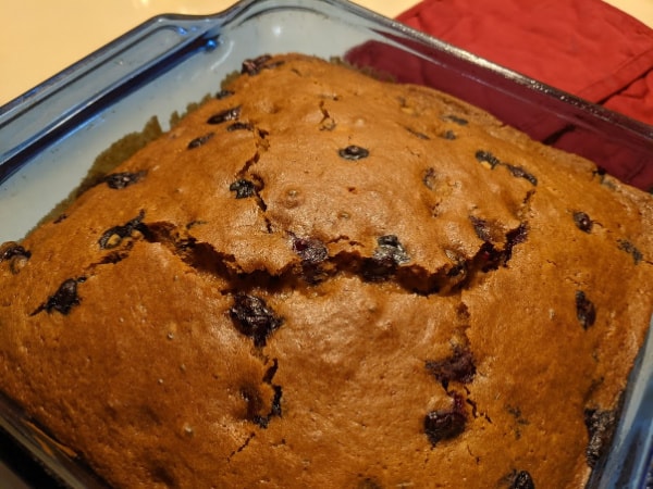 Gluten-Free Blueberry Gingerbread Recipe with cracked top in blue square baking dish. On Gluten Free Easily.