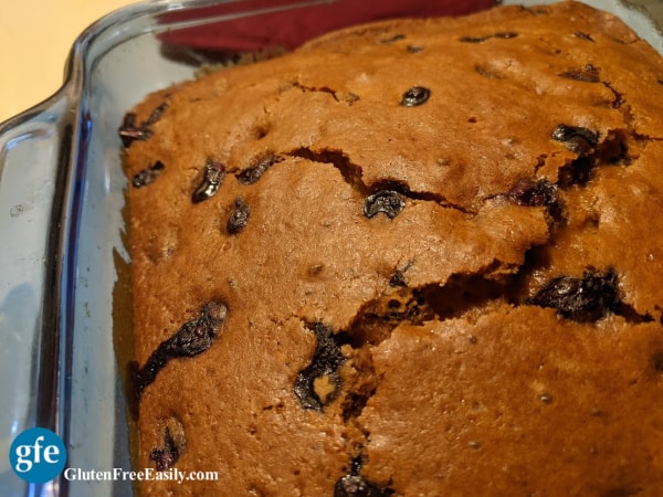 Gluten-Free Blueberry Gingerbread Recipe with cracked top in blue square baking dish. On Gluten Free Easily.