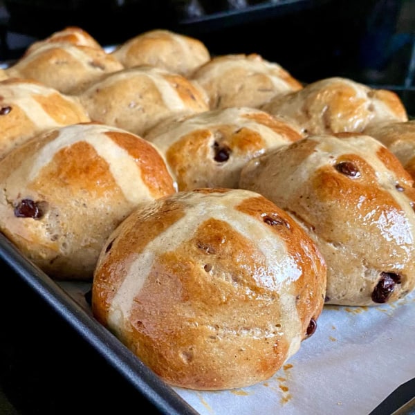 A parchment-lined baking sheet full of side-by-side Gluten-Free Chocolate Chip Hot Cross Buns.