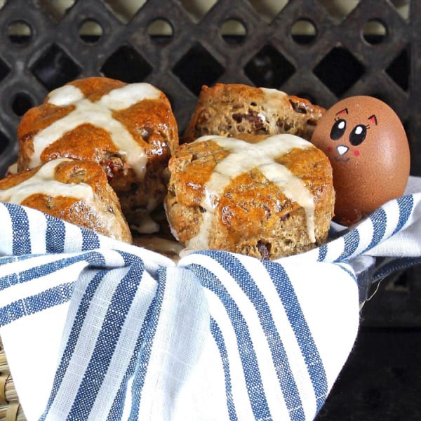 Gluten-Free Hot Cross Scones with an Easter egg decorated with a face in a blue-and-white-striped-towel lined basket.