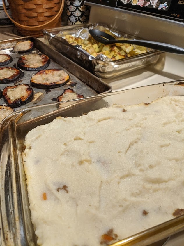 Gluten-Free Shepherd's Pie with Whipped Cauliflower Topping with pans of Eggplant Pizzas and Rosemary Potatoes in background.