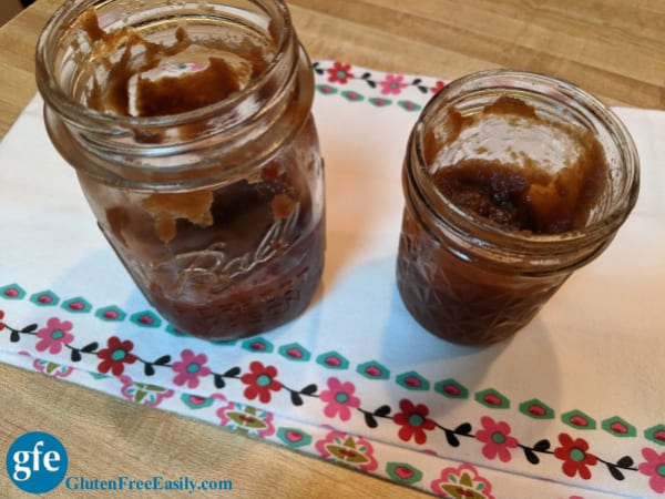 Two half empty pint canning jars with Slow Cooker Apple Butter Made from Applesauce.