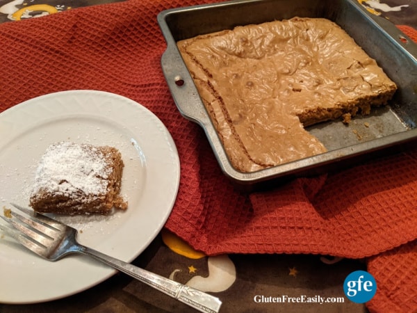 Gluten-Free Caramel Squares in baking dish with one square missing and one corner square with wonderfully chewy edges on a white plate.