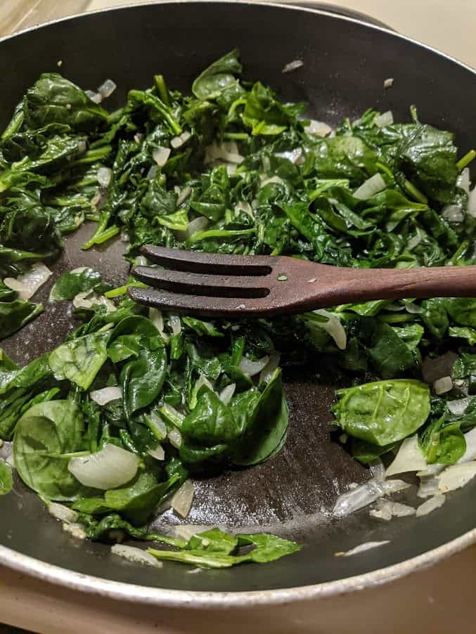 Cooking spinach and onions to make gluten-free Spanakopita Popover.