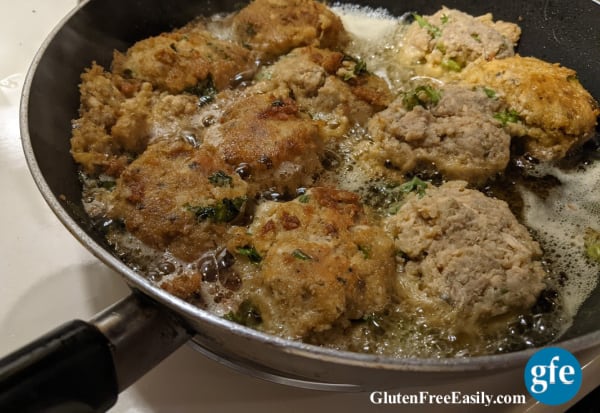 Gluten-Free Quinoa-Crusted Salmon Cakes frying in skillet. Half almost ready to remove, half ready to flip. From glutenfreeeasily.com.