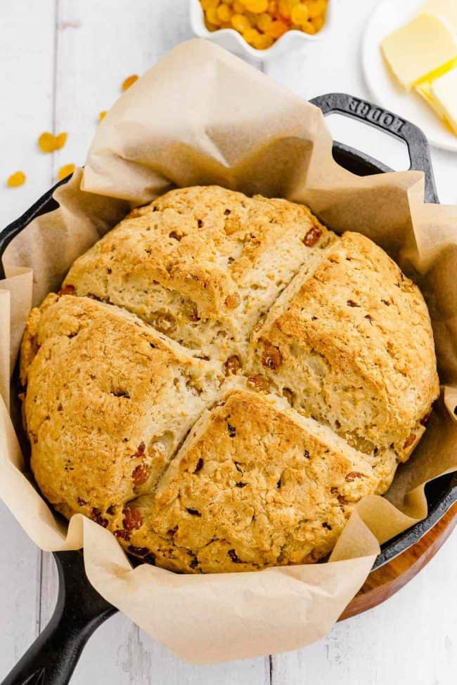 Round loaf of Gluten-Free Irish Soda Bread nestled in parchment-lined baking pan. from Texanerin. One of the gluten-free Irish Soda Bread recipes featured on gfe.
