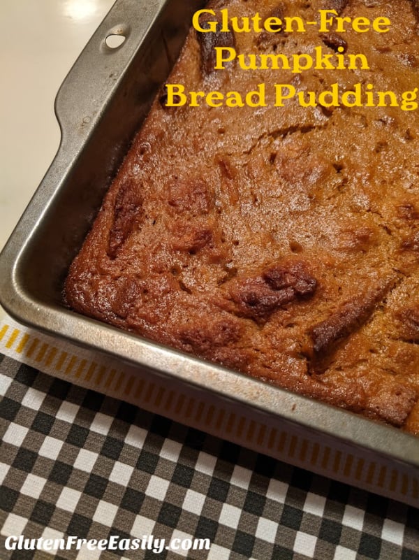 Gluten-Free Pumpkin Bread Pudding in a metal 8 x 8 baking dish right out of the oven cooling on a black gingham dish towel.