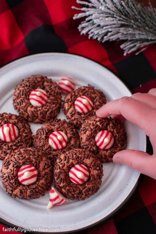 Chocolate Candy Cane Kiss Cookies from Faithfully Gluten Free on white plate with black trim on buffalo plain fabric.