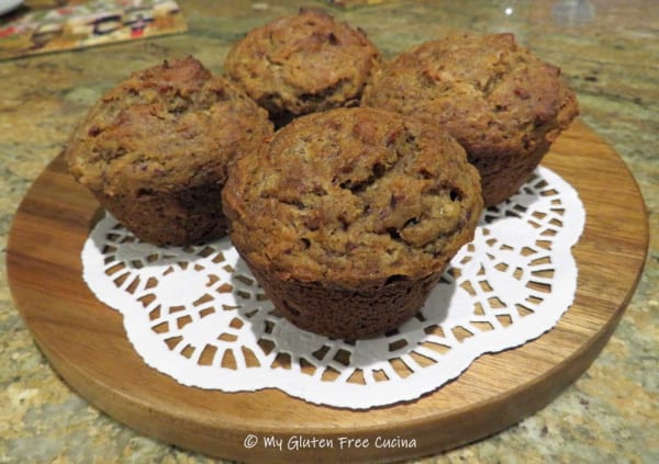 Gluten-Free Banana Date Muffins. Four muffins on a doily on a cutting board.