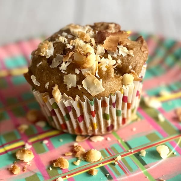 Gluten-Free Taste of the Tropics Muffin on a colorful plaid plate ready to eat with macadamias sprinkled around.