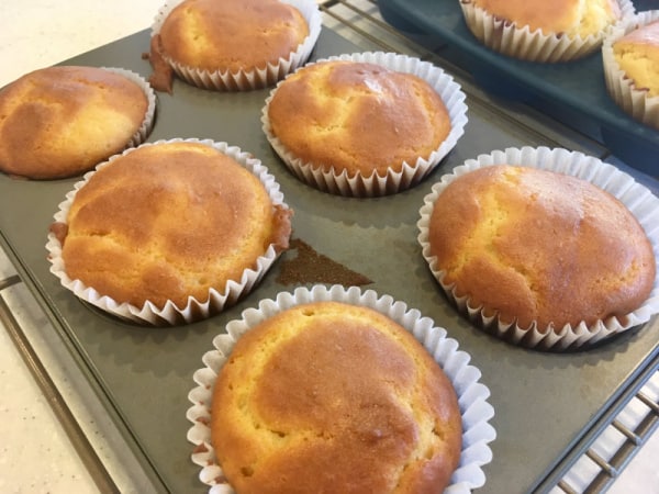 Gluten-Free Light and Fluffy Orange Muffins with Orange Glaze cooling after being baked in larger muffin liners before adding glaze.
