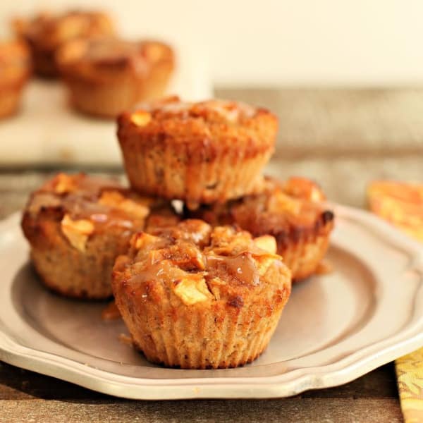 Gluten-Free Paleo Caramel Apple Muffins with low-carb option from Beauty and the Foodie. Stacked high on plate with another plate in background.