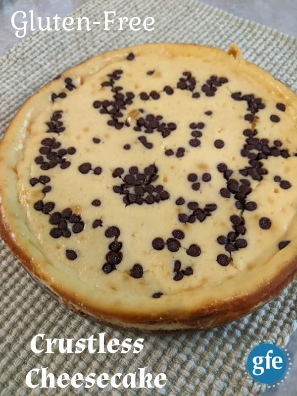 Gluten-Free Crustless Cheesecake with mini chocolate chips, whole, ready to cut, placed on green and white herringbone style placemat.