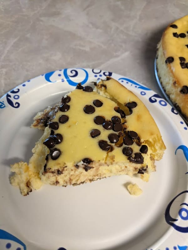 A slice of Gluten-Free Crustless Cheesecake with Mini Chocolate Chips. Luckily, it tastes just as good when it's served on a paper plate!
