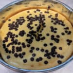 Gluten-Free Crustless Cheesecake with Mini Chocolate Chips added in springform pan right after coming out of the oven.