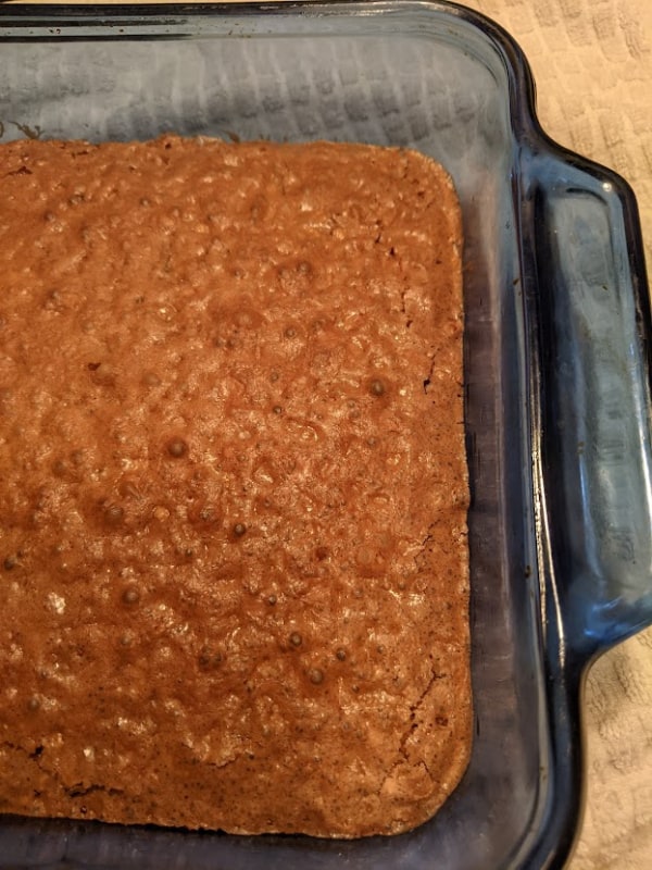 Gluten-Free Katharine Hepburn Brownies in blue glass baking dish right out of the oven. See the crispy and crackly tops.