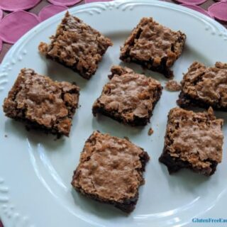 Gluten-Free Katharine Hepburn Brownies on a diagonal on white plate on pink textured table runner.