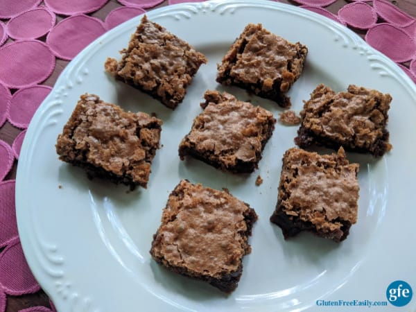 Gluten-Free Katharine Hepburn Brownies on a diagonal on white plate on pink textured table runner.