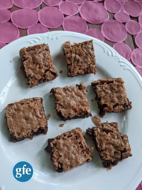 Gluten-Free Katharine Hepburn Brownies on white plate on pink textured background. Brownies are sideways.