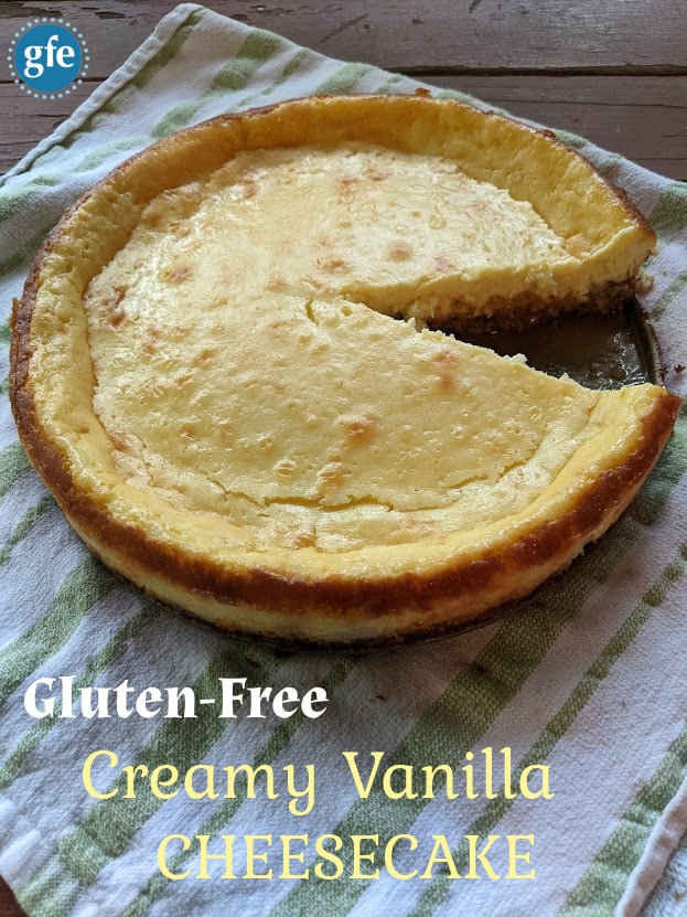 Gluten-Free Creamy Vanilla Cheesecake on a green and white striped towel with a slice missing. 