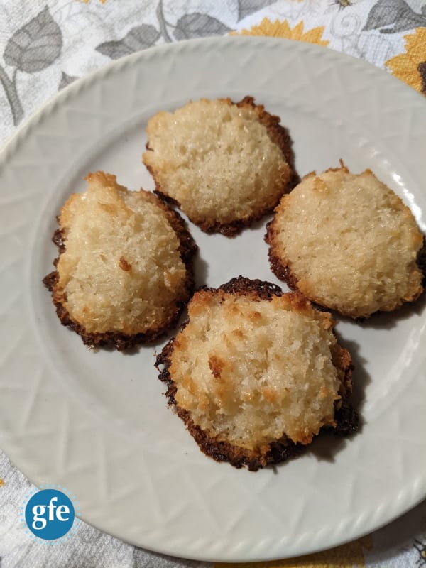 Flourless Gluten-Free Coconut Macaroons made with Let's Do Organic Unsweetened Coconut. Four cookies on a white plate on a sunflower dish towel.