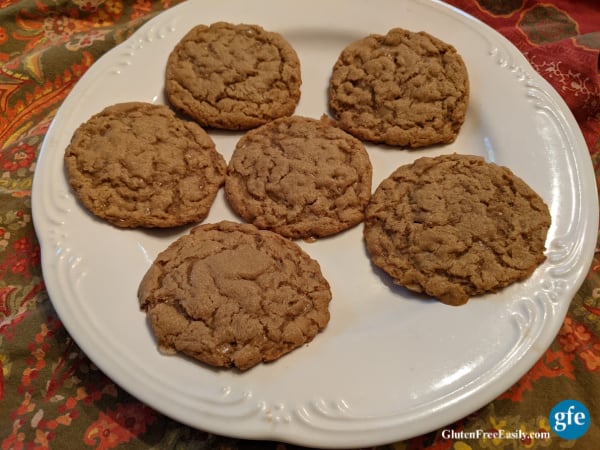 Flourless Peanut Butter Cookies with Toffee Chips (Gluten Free) on white plate with flourishes sitting on brown and orange print apron.