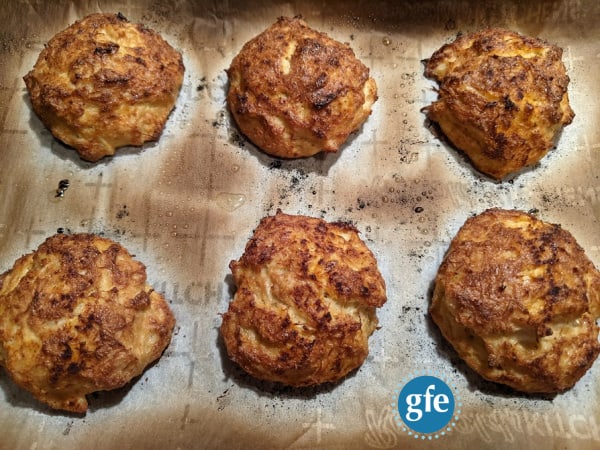 Perfect Gluten-Free Crab Cakes with Old Bay Seasoning right out of the oven and ready to eat. Six crab cakes on parchment-lined baking sheet.