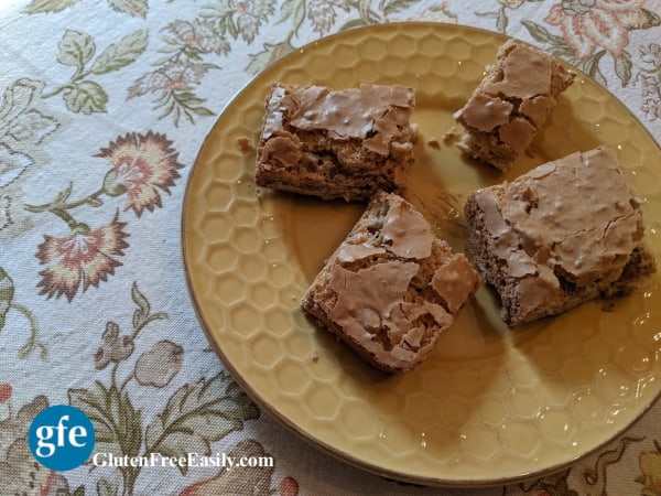 Gluten-Free Chewy Pecan Squares. Plate of four on dining room table with Fall linen tablecloth.