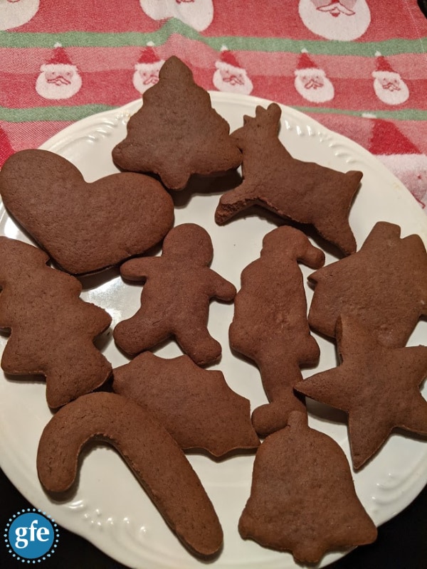 Unfrosted Gluten-Free Chocolate Gingerbread Cookies on a white plate on a Santa dish towel.