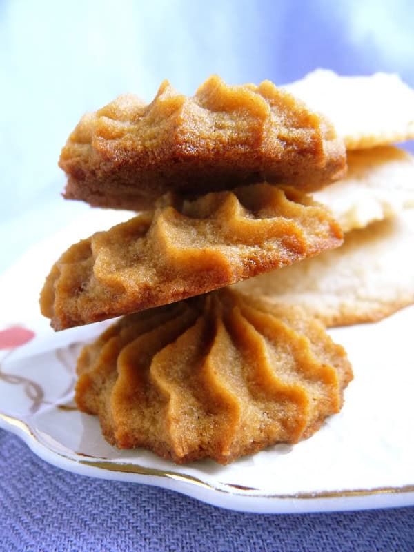 Gluten-Free Cream Cheese Cookies. Not just gluten free but also dairy free, egg free, and vegan. Shown as drop cookies made with granulated white sugar on the left and a stack of piped cookies made with coconut/palm sugar on the right.