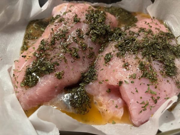Gluten-Free Zesty Turkey Breast Tenderloins with ingredients poured over them in parchment-lined baking dish ready to go in the oven.