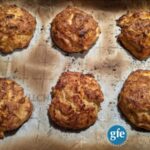 Perfect Gluten-Free Crab Cakes with Old Bay Seasoning right out of the oven and ready to eat. Six crab cakes on parchment-lined baking sheet.